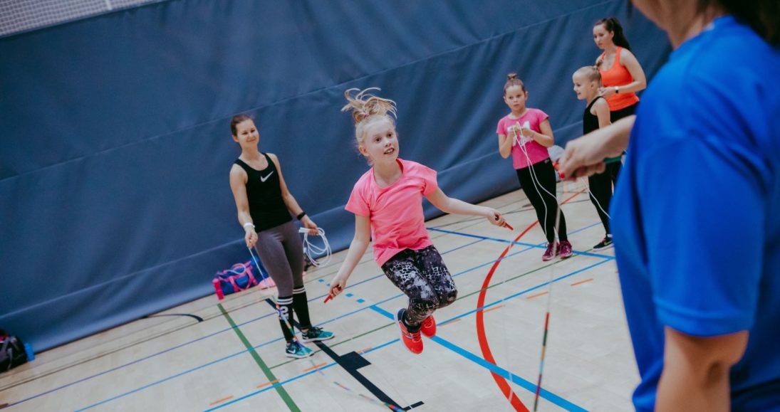 Lapset hyppäävät narua liikuntasalissa.