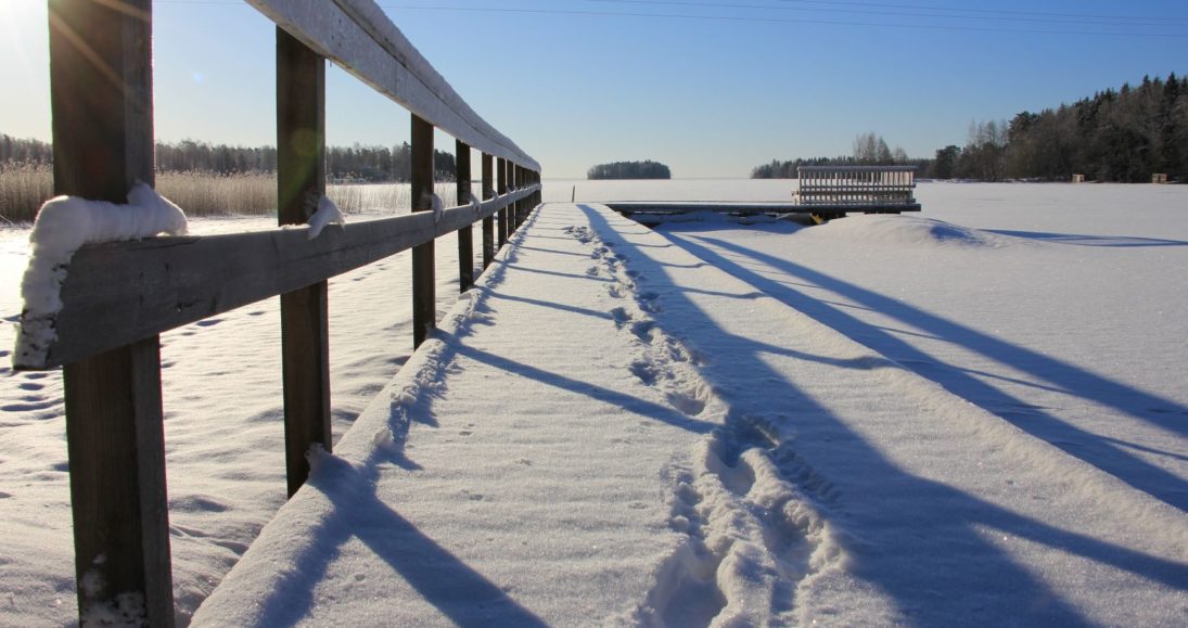 Talvinen maisema laiturilta järvelle, aurinko paistaa.