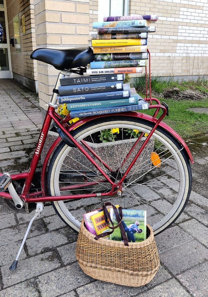 Punaisen polkupyörän tarakalla iso pino kirjoja